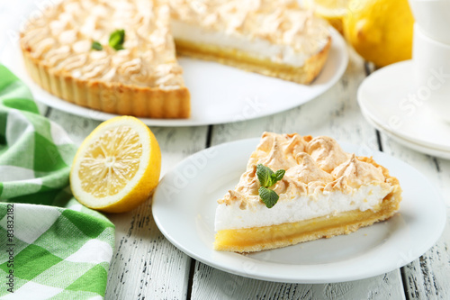 Lemon meringue pie on plate on white wooden background