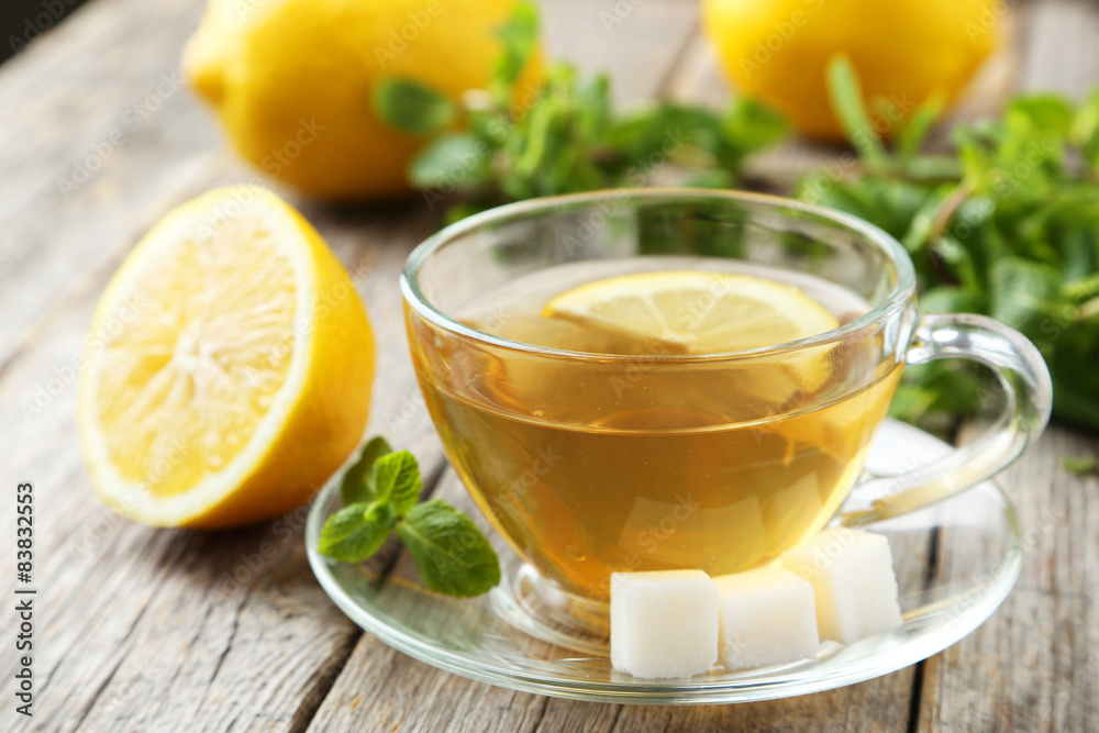 Cup of tea with mint and lemon on grey wooden background Cup of tea with mint and lemon on grey wooden background