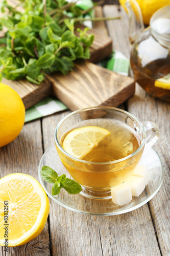 Cup of tea with mint and lemon on grey wooden background