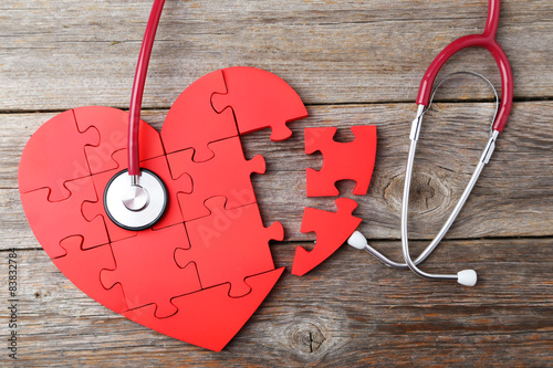 Принти на полотні Red puzzle heart with stethoscope on grey wooden background