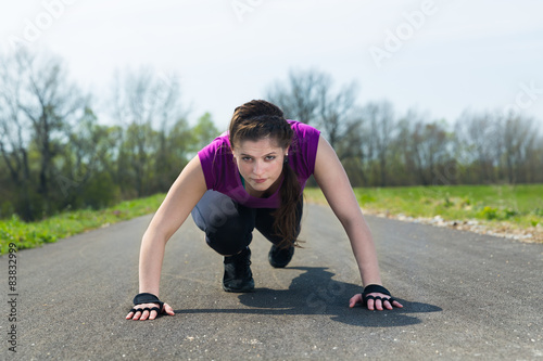 Woman in start position on track wait for start runner workout.
