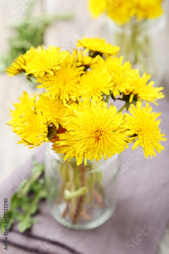 Yellow dandelion on grey wooden background