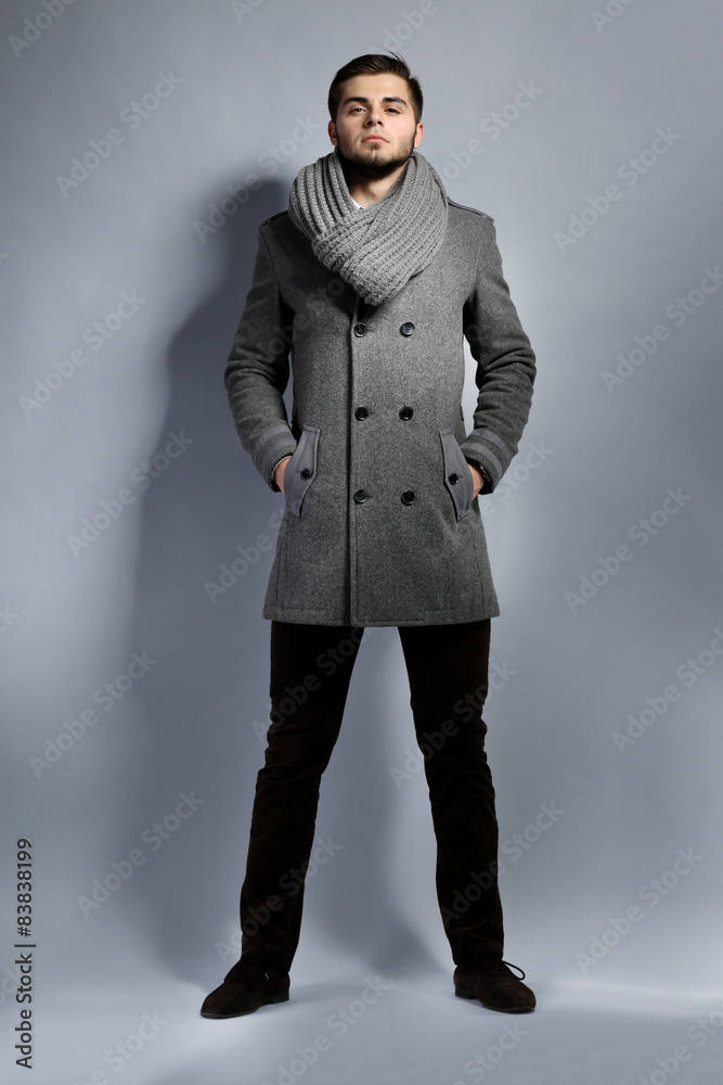 Young man in coat on gray background Young man in coat on gray background