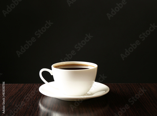 Cup of coffee on wooden table  on dark background
