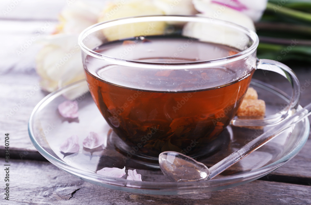 Cup of herbal tea with tulips on wooden table, closeup
