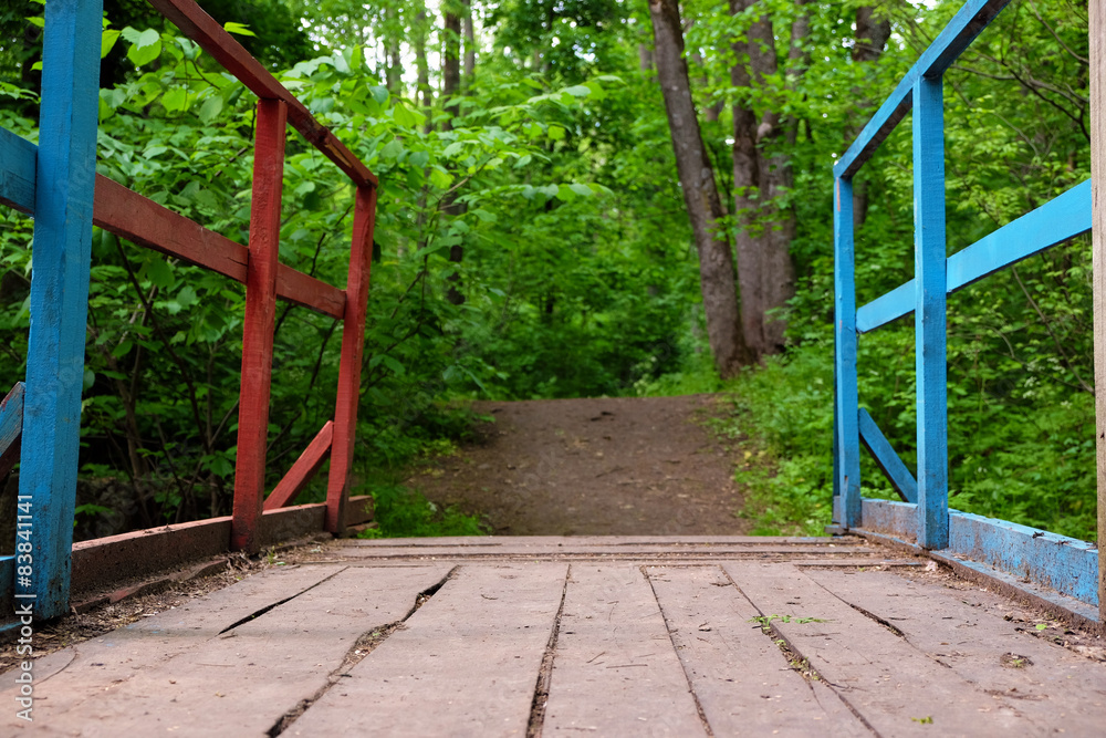 Wooden bridge in park over green trees background Wooden bridge in park over green trees background