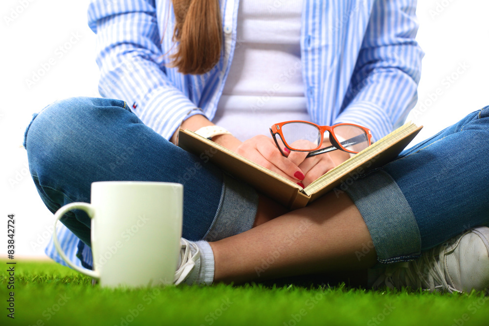 Obraz premium Woman reading book sits on the green grass