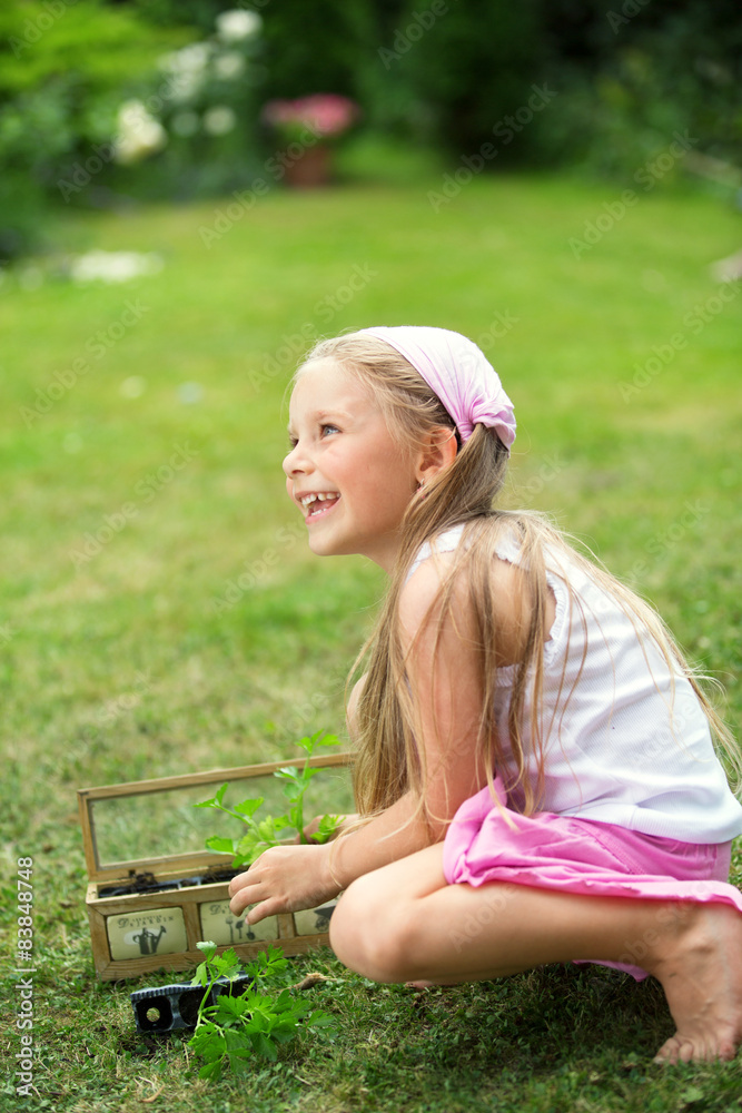 Mädchen im Garten pflanzt Kräuter an StockFoto Adobe Stock