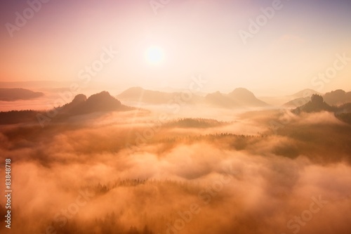 Marvelous red daybreak. Misty beautiful peaks of hills in fog