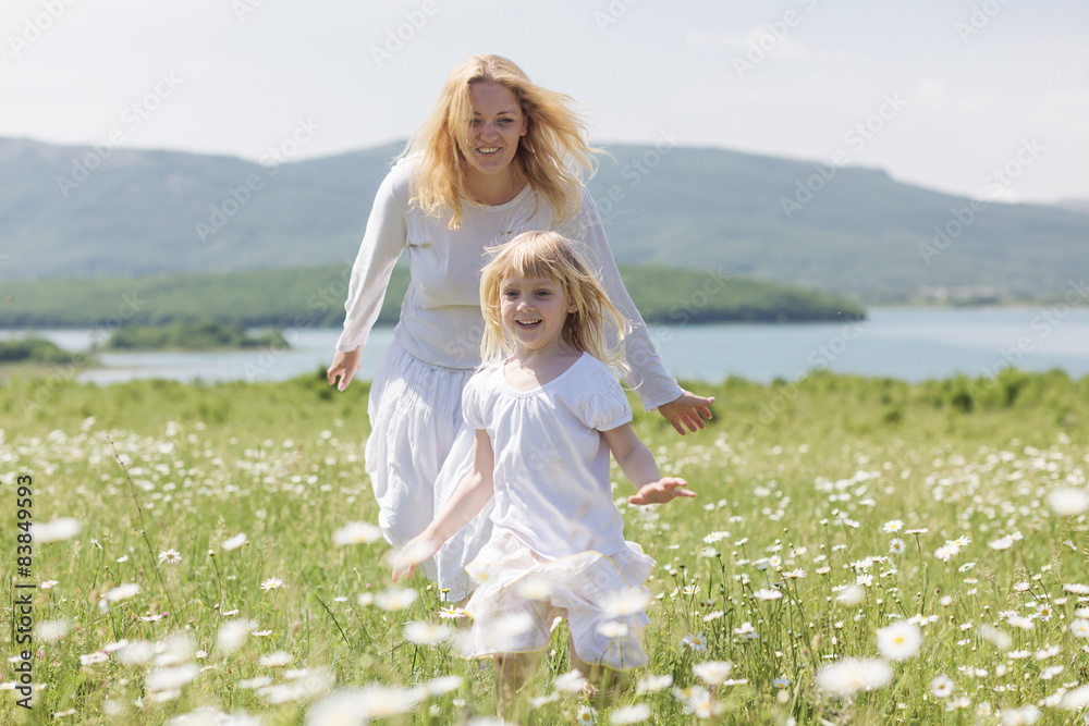 Happy mother playing with her daughter in flower field