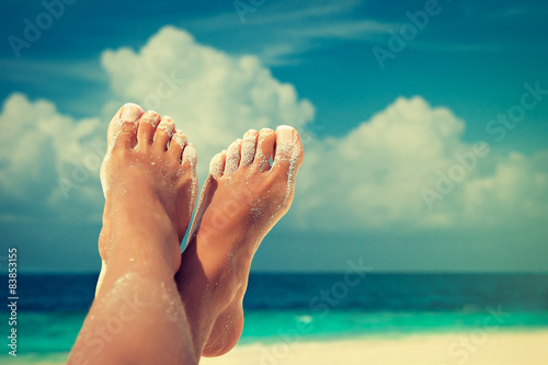 Tanned well-groomed feet amid tropical turquoise sea

