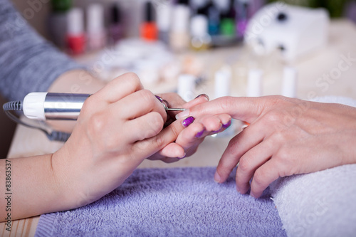 Manicure technician polishing fingernails by polish nail machine
