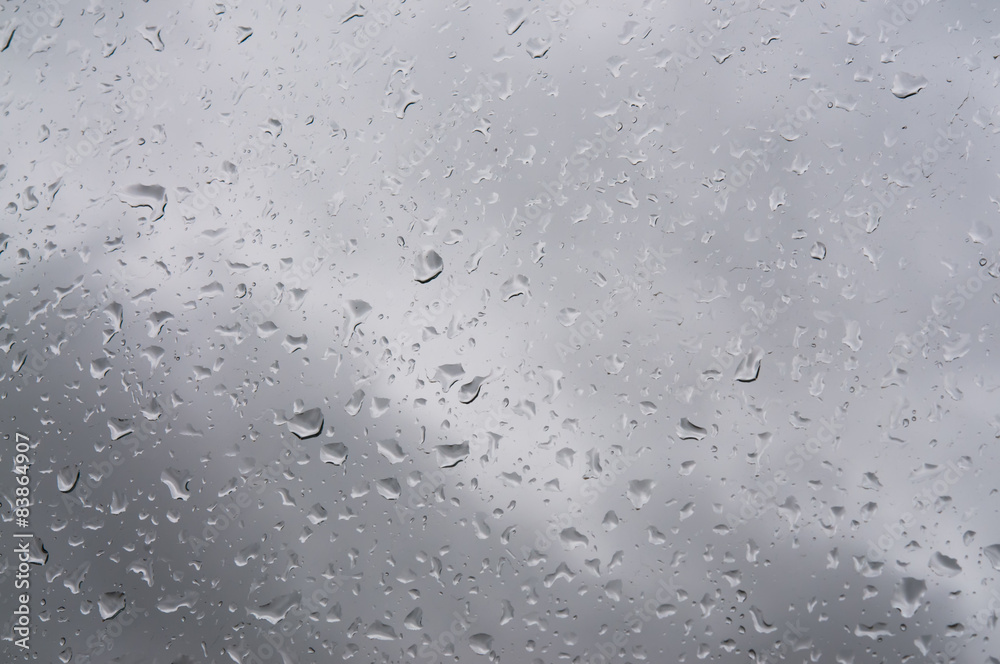 Rain waterdrops on glass surface against gray sky clouds Rain waterdrops on glass surface against gray sky clouds
