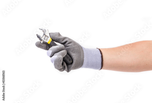 Hand in gloves holding adjustable wrench.
