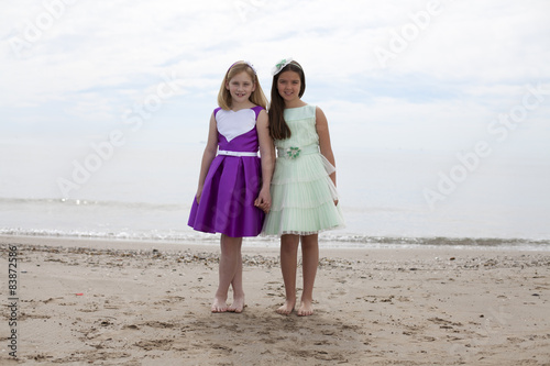 Принти на полотні Niñas rubia y castaña cogidas de la mano en la playa
