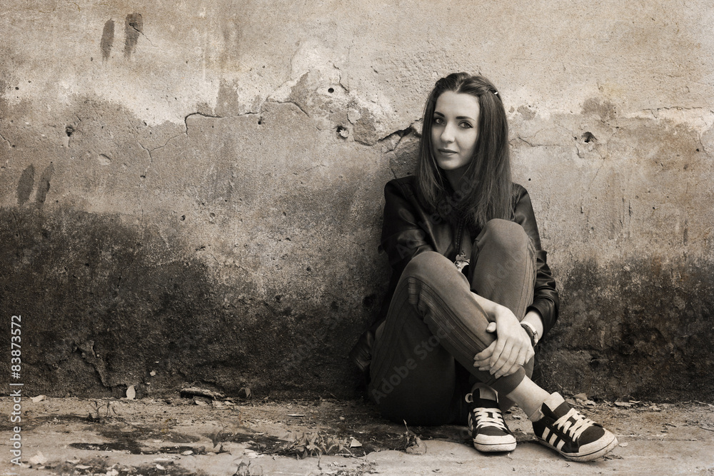 Artwork in retro style, young woman sitting near the rough wall
