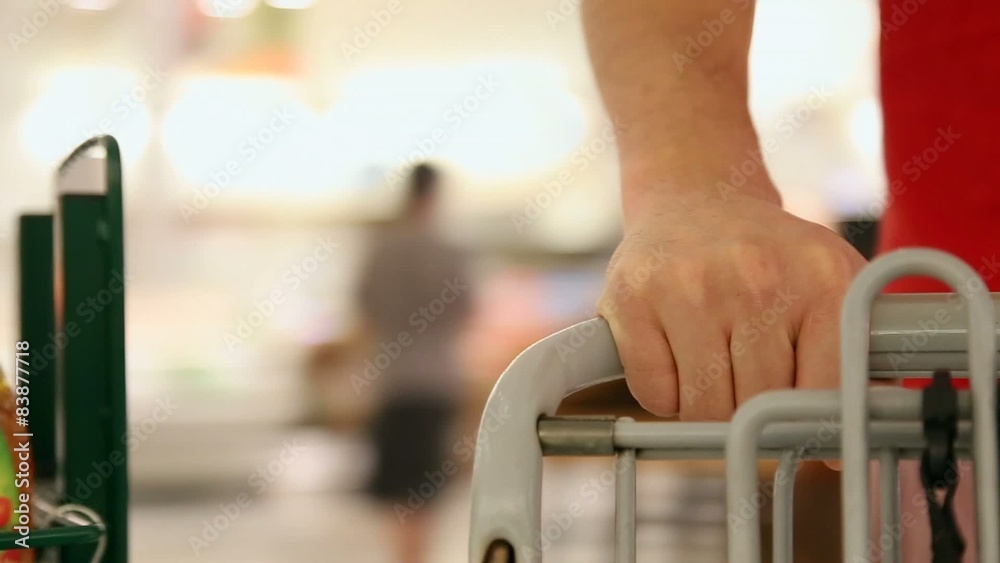 Hand pushing cart at supermarket