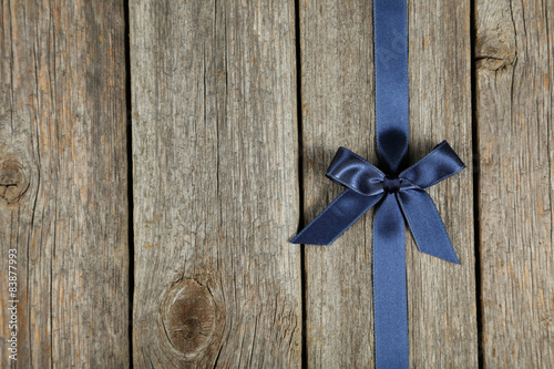 Blue ribbon with bow on grey wooden background