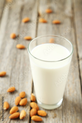Glass of milk with almonds on grey wooden background