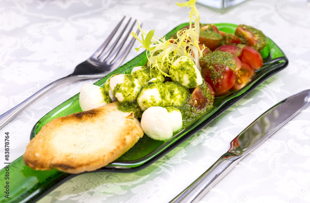 Caprese salad with tomatoes and cheese in a plate of glass Caprese salad with tomatoes and cheese in a plate of glass