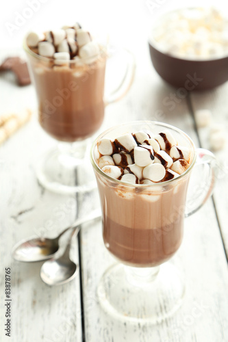 Glasses of hot chocolate with marshmallows on white wooden backg