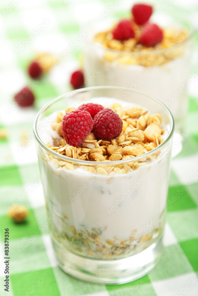 Muesli with yogurt and raspberries in a glass on napkin Muesli with yogurt and raspberries in a glass on napkin