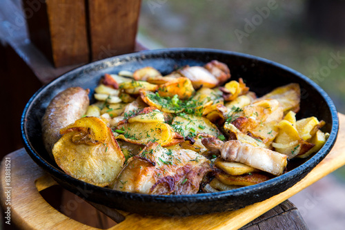rustic lunch with potato and bacon in iron pan outdoor