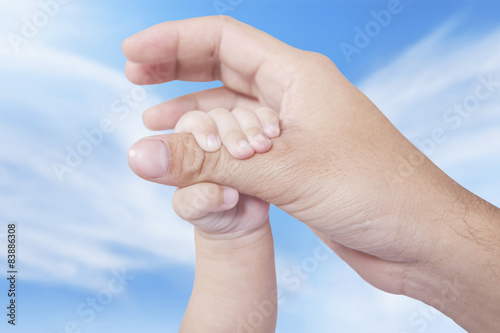 Infant hand holds father finger © Creativa Images