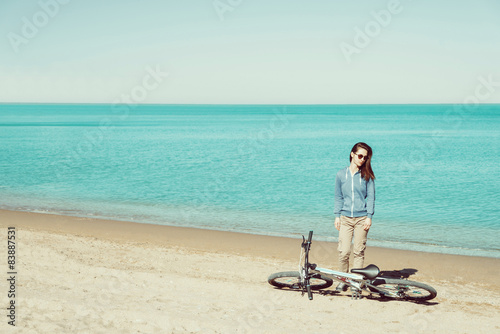 Girl with a bicycle standing on beach