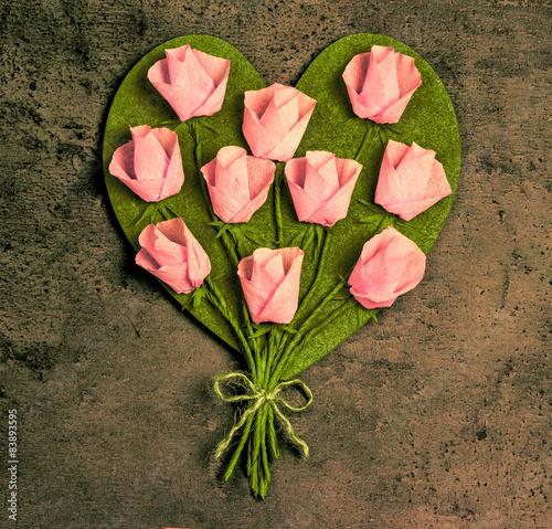 Pink roses in a heart shape on vintage wooden background