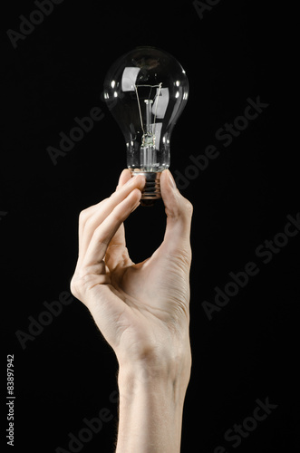 human hand holding a light bulb on black background in studio