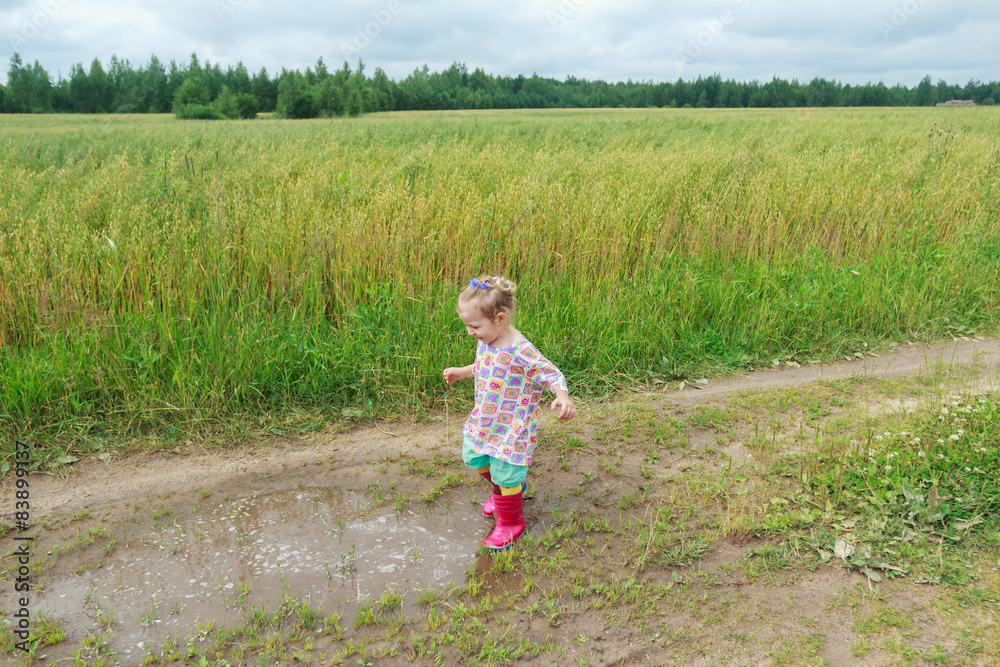 Blonde curly preschooler girl playing on farm dirt road near Blonde curly preschooler girl playing on farm dirt road near