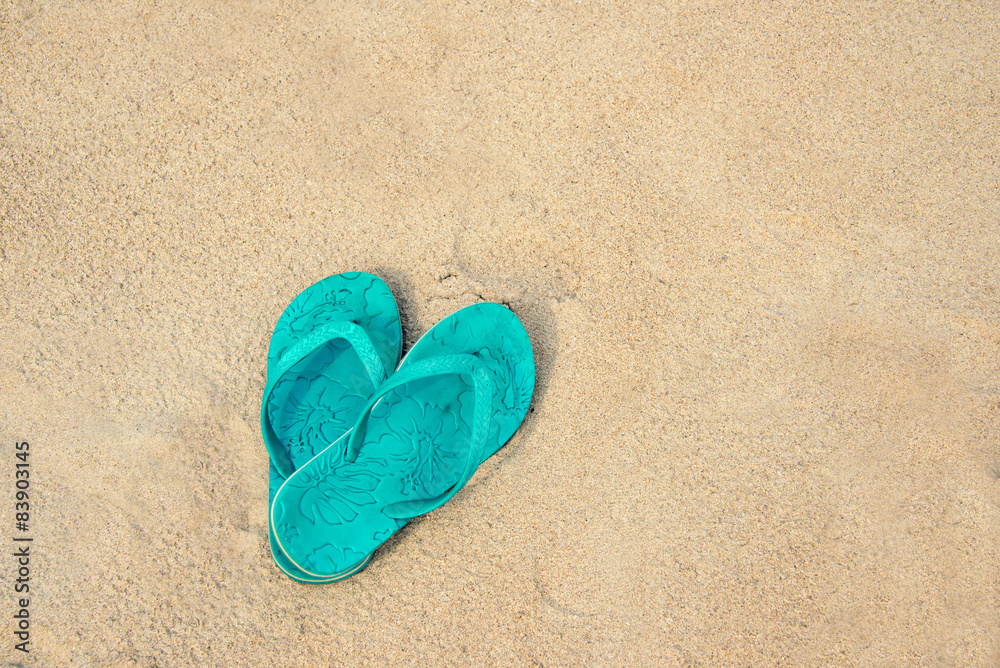 Blue pair of flip flops on the beach, summer concept