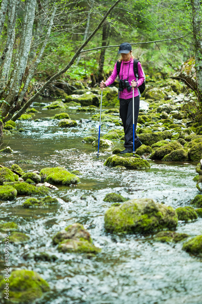 Hiker in forest crossing the stream Hiker in forest crossing the stream