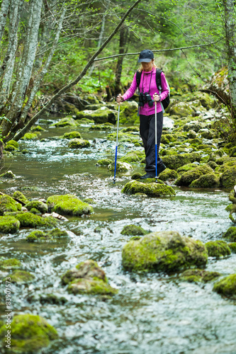 Hiker in forest crossing the stream