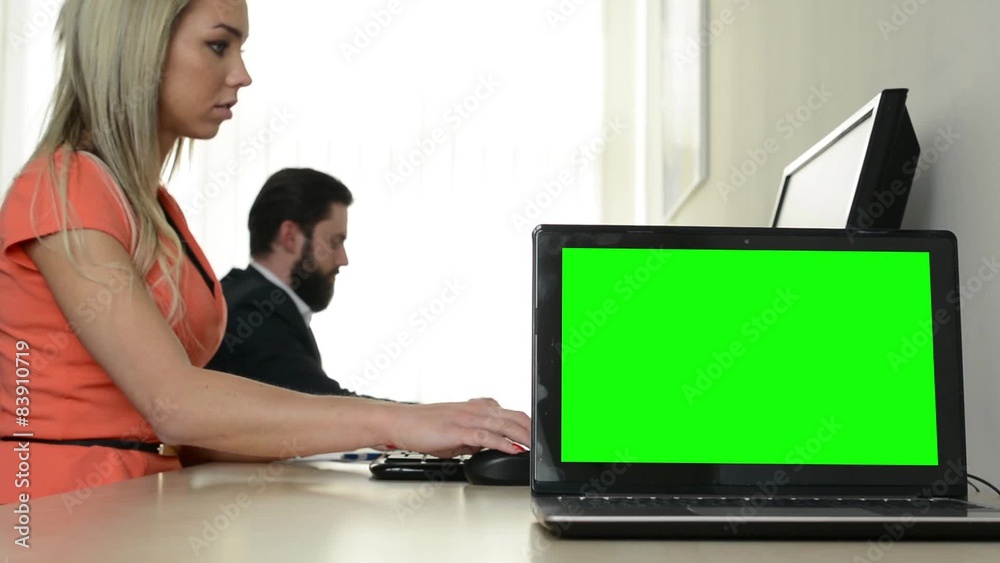computer (laptop) - green screen - man and woman work on the computer in the office in the background computer (laptop) - green screen - man and woman work on the computer in the office in the background