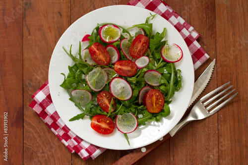 salad with radish on plateon brown background