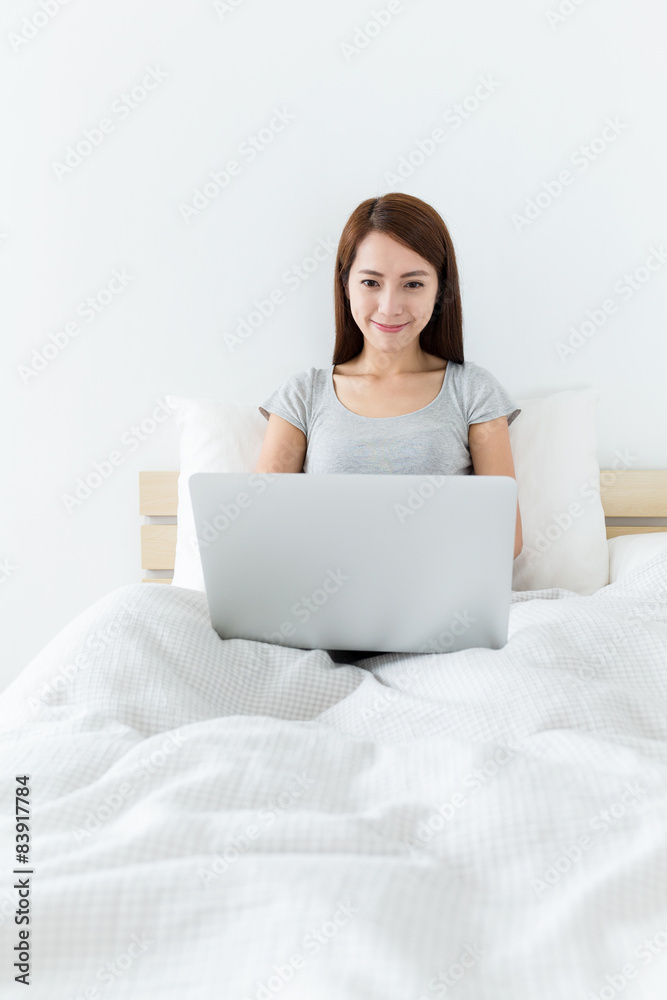 Asian woman use of notebook computer and sitting on the bed Asian woman use of notebook computer and sitting on the bed