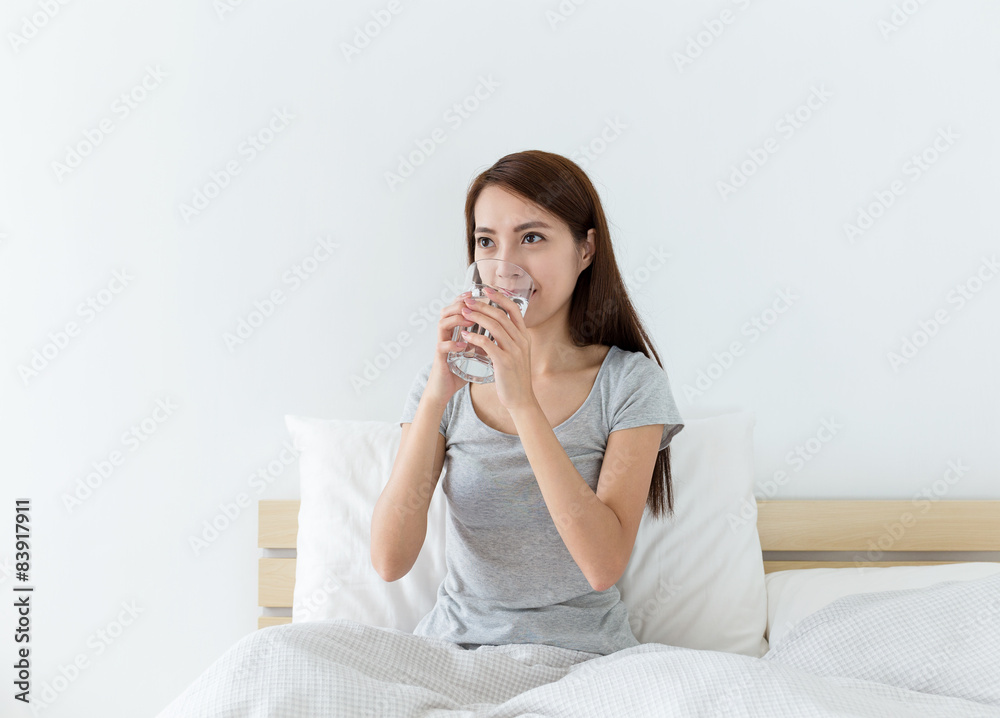 Woman drinking water on the bed