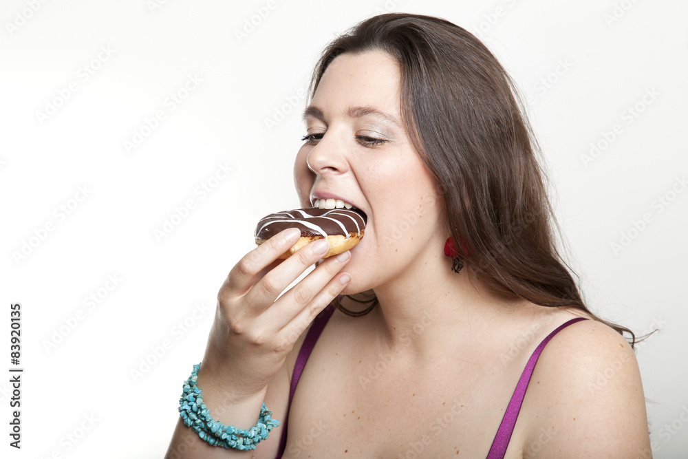 Frau beißt herzhaft in einen Schokodonut Frau beißt herzhaft in einen Schokodonut
