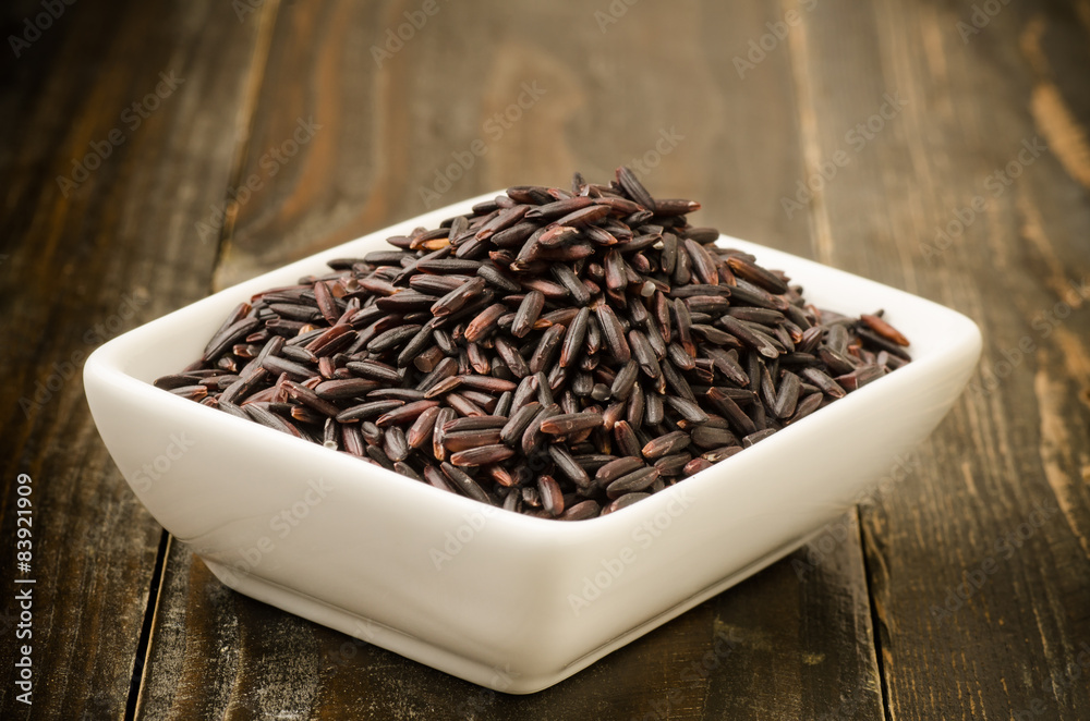 Brown rice (Rice berry) in the bowl on wooden background Brown rice (Rice berry) in the bowl on wooden background