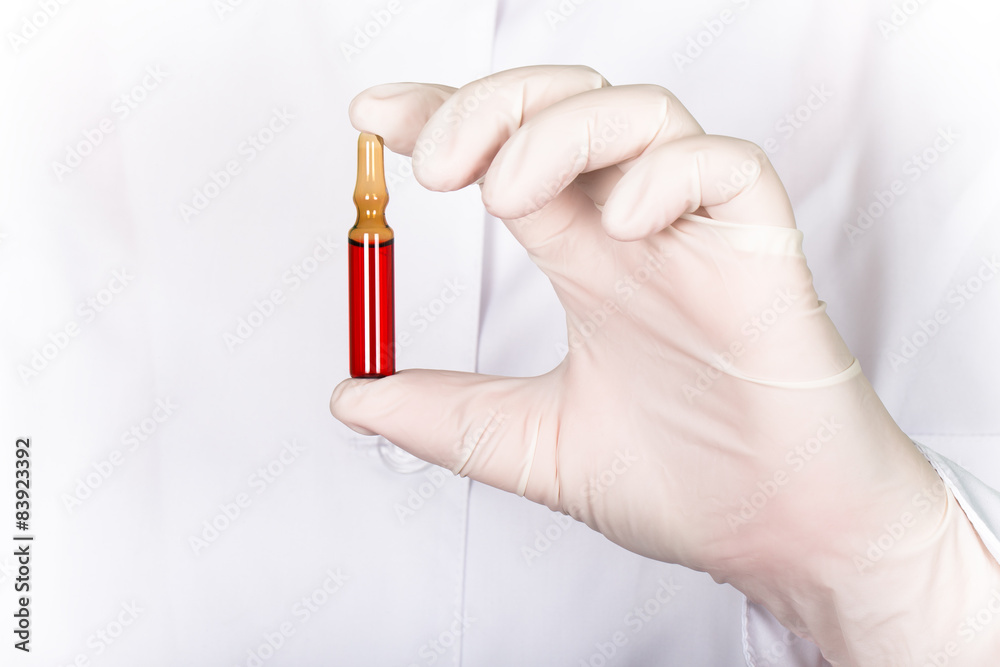 A gloved hand holding a ampoule with medicine on a background of A gloved hand holding a ampoule with medicine on a background of