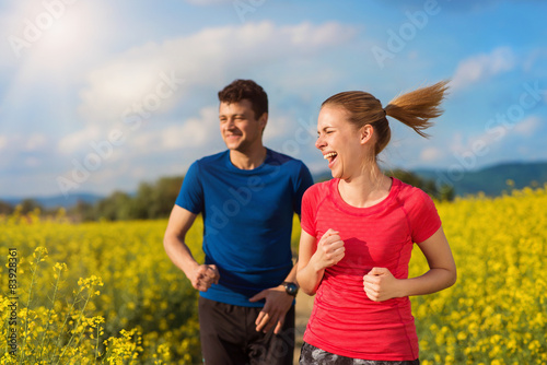 Beautiful young couple jogging outside in canola field