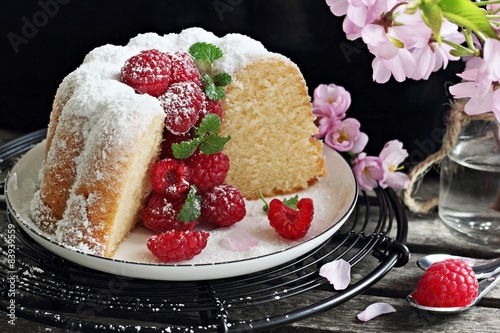 Vanilla cake with fresh raspberries on a rustic dark background  photo