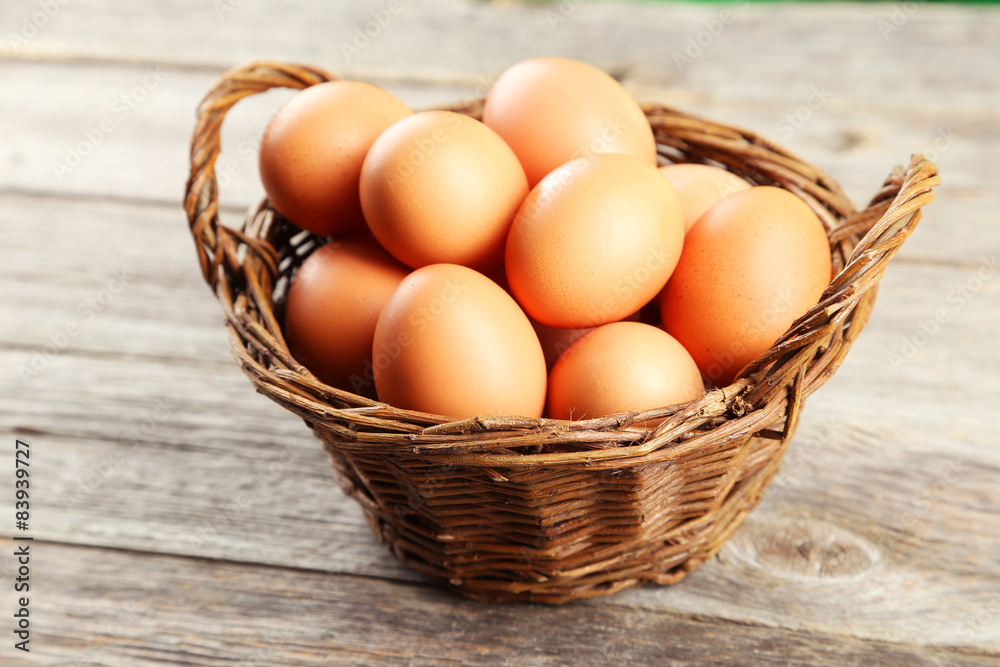 Chicken eggs in basket on grey wooden background Chicken eggs in basket on grey wooden background