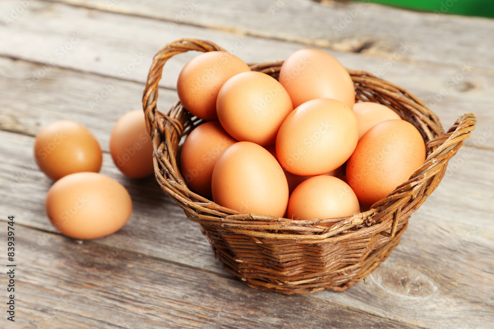 Chicken eggs in basket on grey wooden background Chicken eggs in basket on grey wooden background