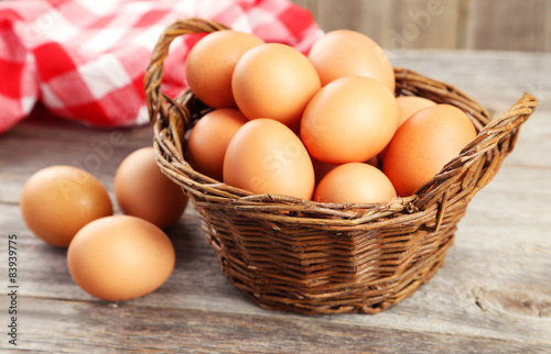 Chicken eggs in basket on grey wooden background
