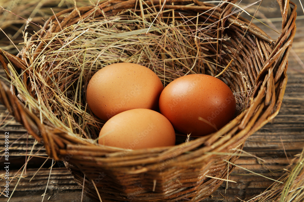 Eggs in basket on brown wooden background