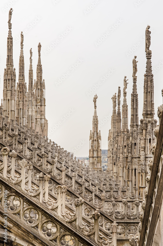 Vertical view of stone sculptures on roofs of Duomo Milano