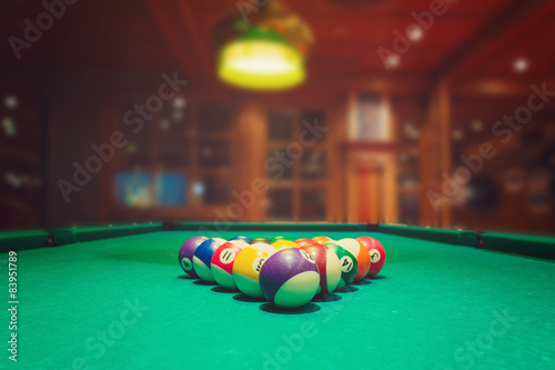 Billiard balls on green pool table in bar or pub